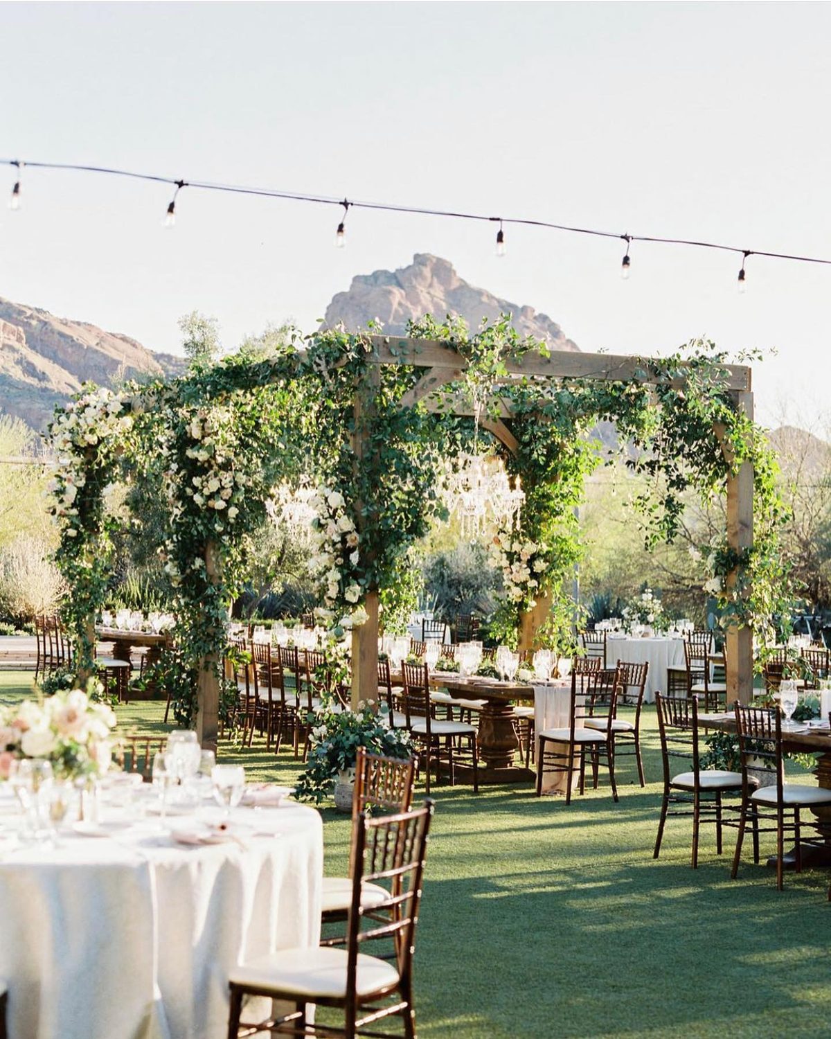 El Chorro's event lawn set for dinner under a vine-covered pergola, Camelback Mountain behind