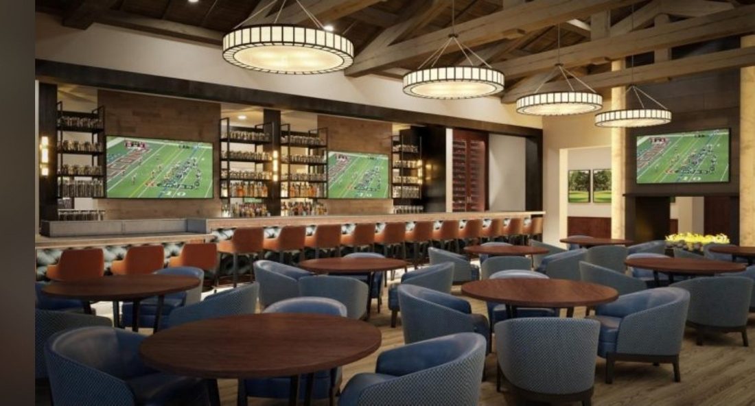 The Silverleaf Club clubhouse bar and lounge — a long bar with bottle shelves and game screens, lounge tables and armchairs under ring chandeliers
